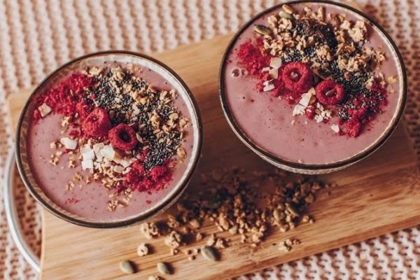 moothie Buah Naga: Gelas berisi smoothie berwarna merah muda dengan hiasan potongan buah naga di pinggirnya
