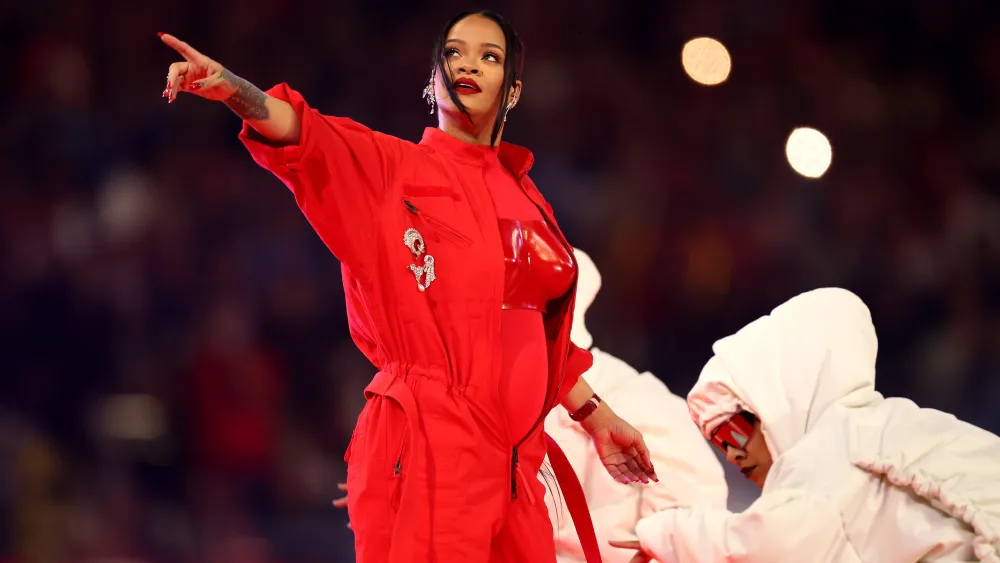 Rihanna tersenyum lebar di atas panggung dengan mikrofon di tangan