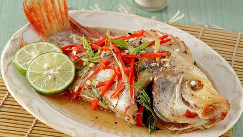 Ikan mas kukus dengan bumbu rempah dan pelengkap sayuran segar, disajikan hangat untuk menu sehat Anda