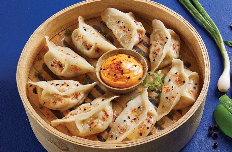 Crispy fried Momos arranged on a plate with dipping sauce 